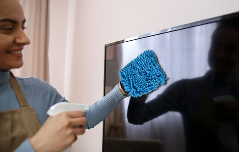 A woman using a microfiber electronics cleaning cloth to clean an LED TV screen