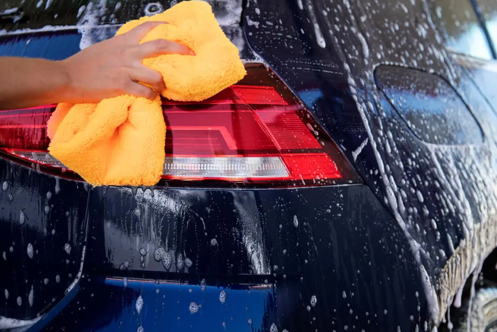 A person is cleaning a car with a microfiber in his hand